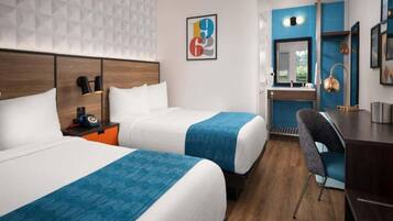 A hotel room with two beds, a desk, and a chair.