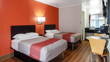 A hotel room with two beds, a desk, a chair, and a television.