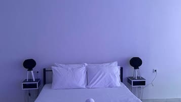 A neatly made bed with white linens, a pair of glasses, and a rolled towel on the bed.