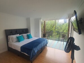 A bedroom with a bed, a balcony with a chair, and a fan. - Charming 2-Bedroom Apartment in Medellín's Golden Mile (Medellín)