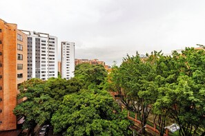 A high-rise building with multiple floors, surrounded by lush green trees. - Charming 2-Bedroom Apartment in Medellín's Golden Mile (Medellín)
