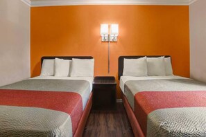 A hotel room with two beds, a nightstand, and a wall-mounted light fixture.
