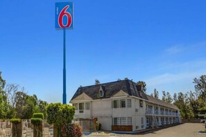 A motel with a prominent '6' sign, a two-story building with a flat roof, and a parking lot.