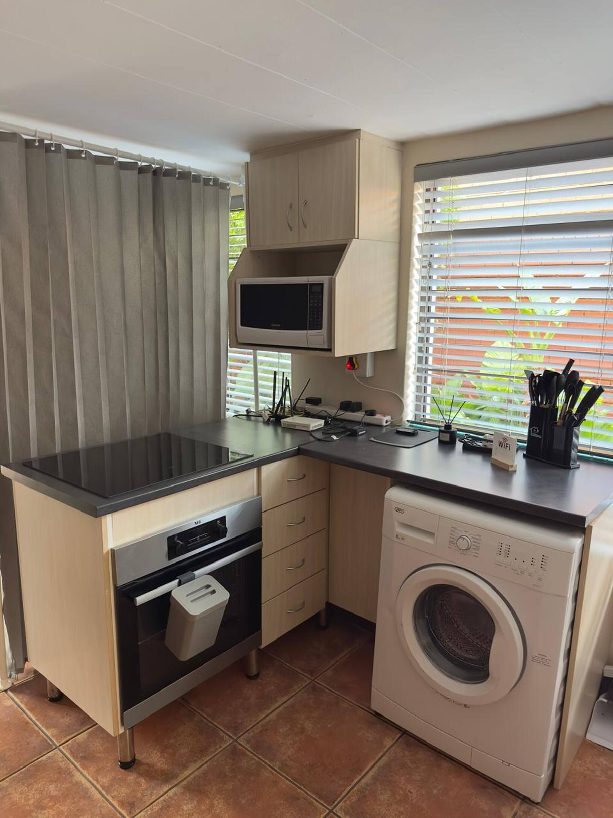 A compact kitchen with a microwave, oven, and washing machine.