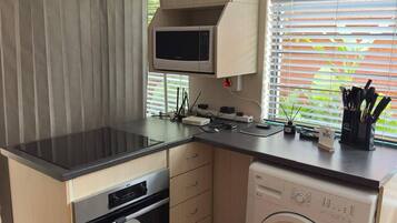 A compact kitchen with a microwave, oven, and washing machine.