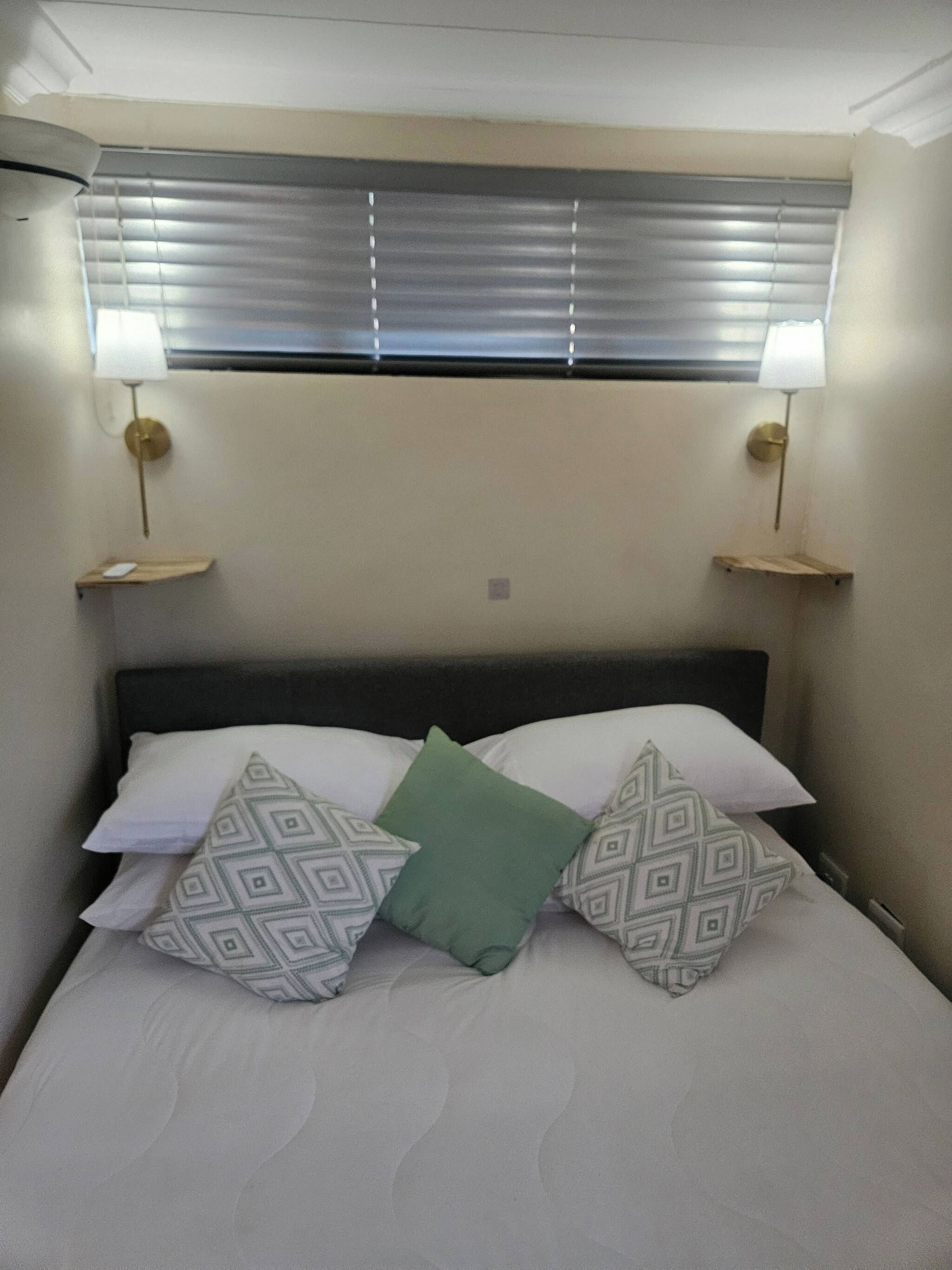 A bed with patterned pillows, a headboard, and two bedside lamps.