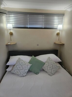 A bed with patterned pillows, a headboard, and two bedside lamps. - On the Ridge Apartment (Pretoria)