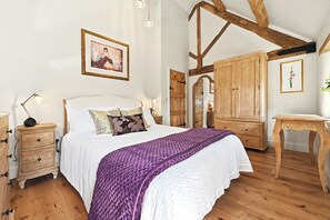 A bedroom with a bed, wooden furniture, a wardrobe, and a painting on the wall. - Butterton Barn (Leek)
