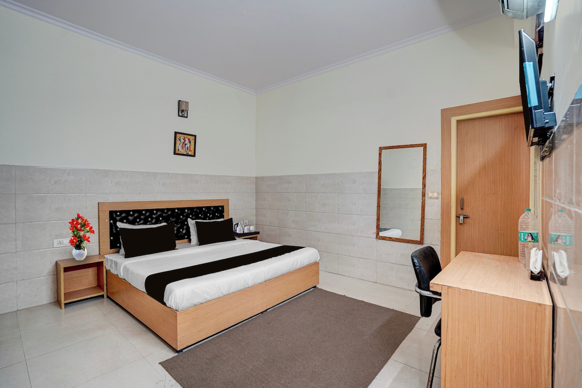 A hotel room with a bed, bedside table, a mirror, a desk, and a chair.