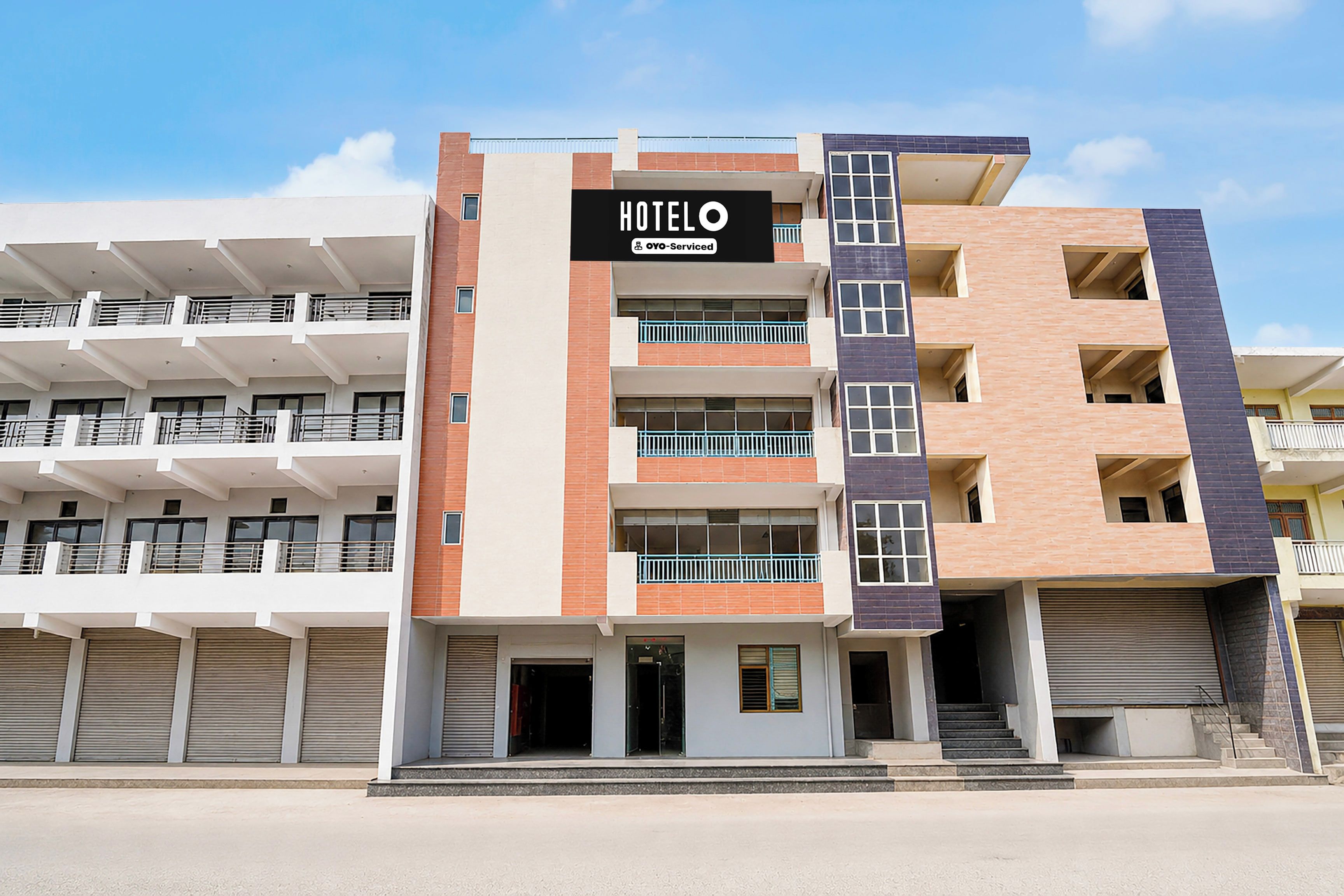 Un hotel de varios pisos con un llamativo letrero que dice 'HOTEL', balcones y un diseño arquitectónico moderno.