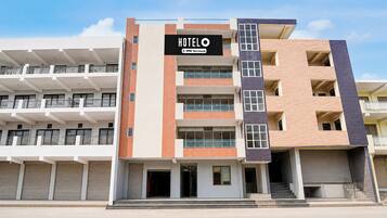 Un hotel de varios pisos con un llamativo letrero que dice 'HOTEL', balcones y un diseño arquitectónico moderno.