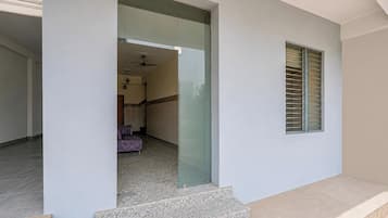 Un interior moderno con puerta de cristal, suelo estampado y una ventana con persianas horizontales.