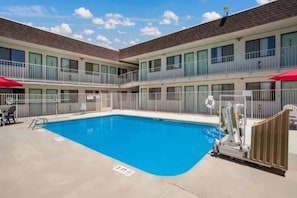 A hotel with a pool, outdoor seating, and a fenced area. - 1 Queen Bed | Non-Smoking, Micfridge (Grand Junction)