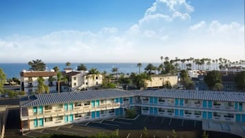 A motel with a parking lot and a view of the ocean.