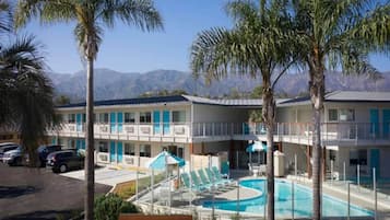 Un hôtel doté d’une piscine, de palmiers et ayant des montagnes en toile de fond.