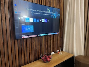 Un téléviseur à écran plat fixé à un mur en bois, affichant une interface Smart Hub avec différentes icônes d’applications.