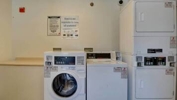 A laundry area with a washing machine, dryer, and a sign indicating the motel is not responsible for unattended items.