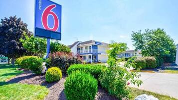 A motel with a prominent '6' sign, a welcoming entrance, and well-maintained landscaping.