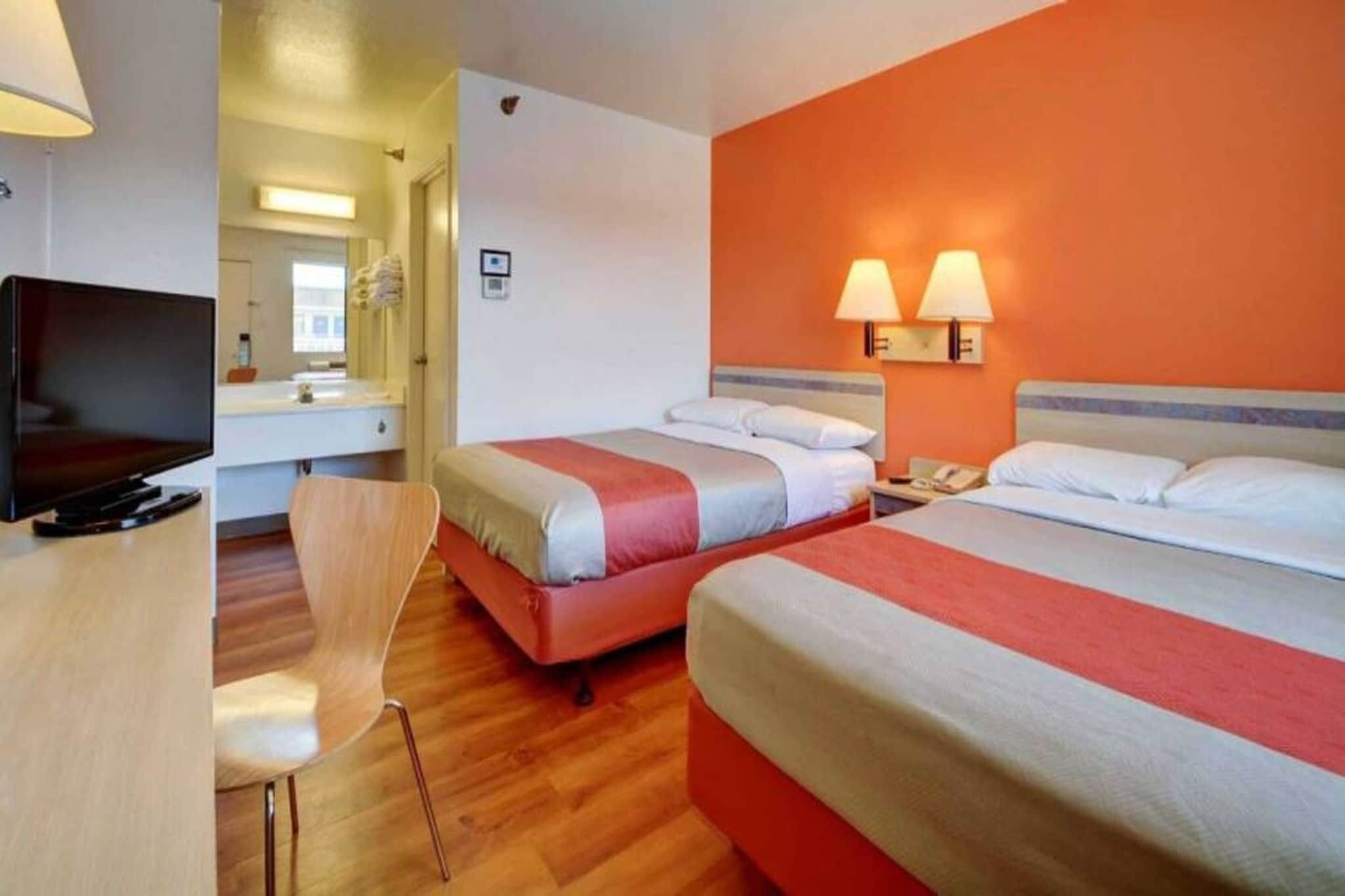 Una habitación de hotel con dos camas, televisión, escritorio y una silla.