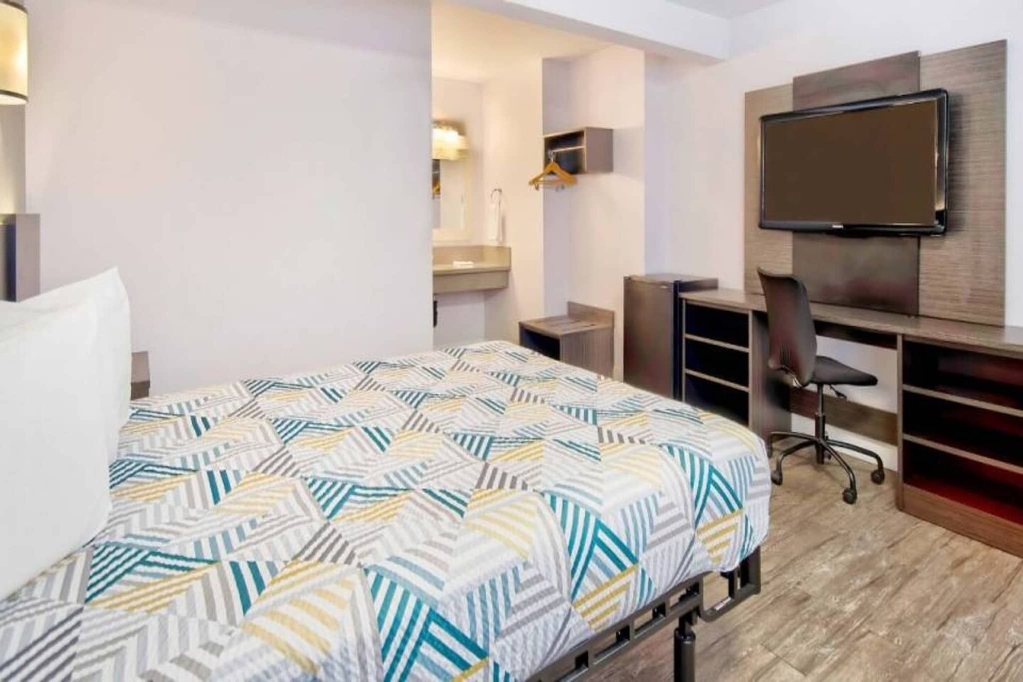 Une chambre d’hôtel équipée d’un lit, d’un bureau, d’une chaise, d’une télévision et d’une armoire.
