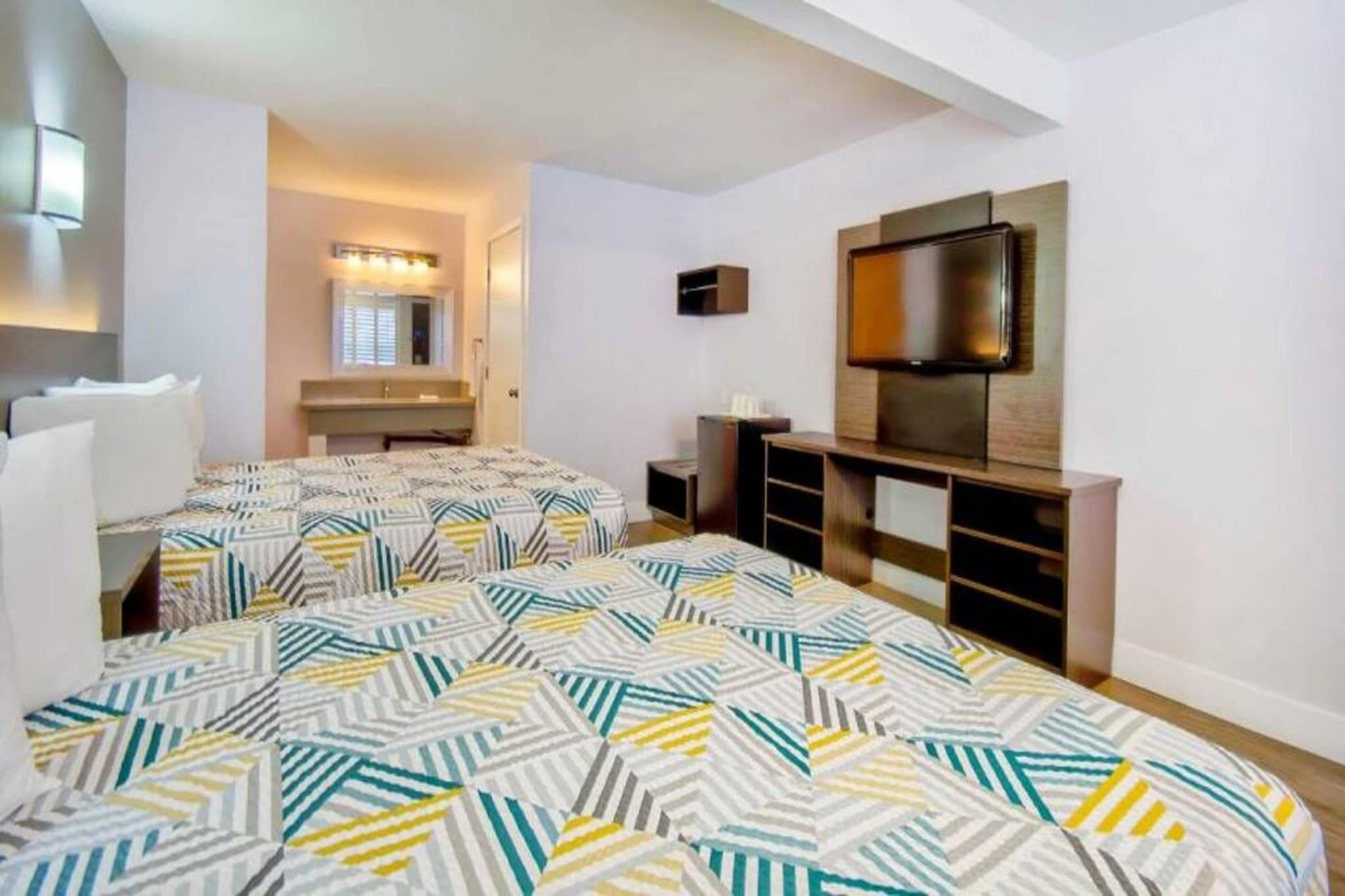 Een hotelkamer met twee bedden, een televisie, een bureau en een badkamer.