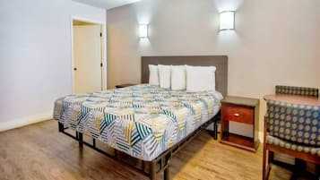 Een slaapkamer met een bed, nachtkastje, stoel en een deur.