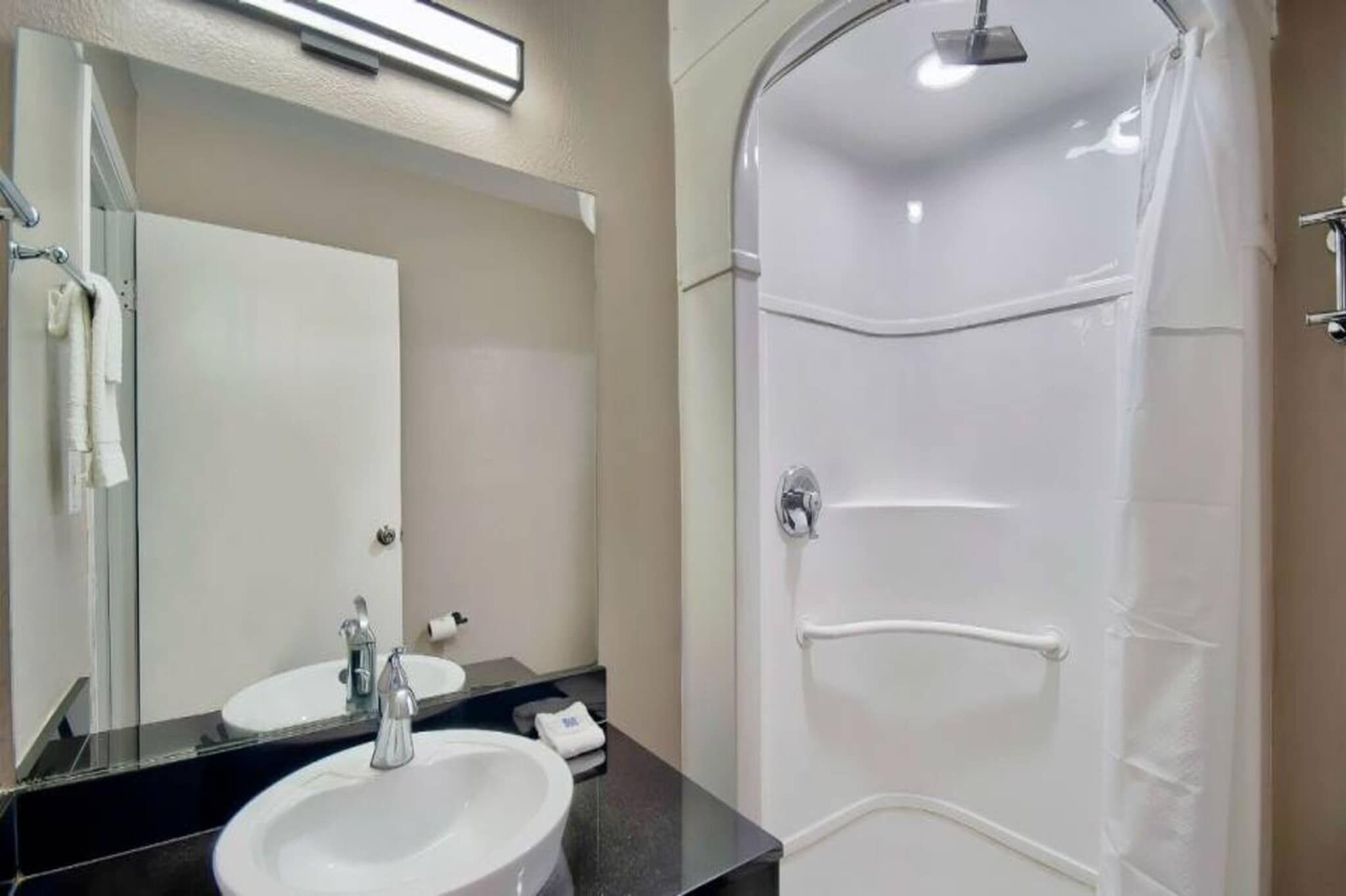 A bathroom with a sink, mirror, and shower.