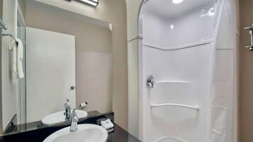 A bathroom with a sink, mirror, and shower.