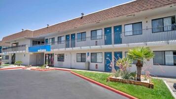 A motel with a 'welcome' sign, multiple balconies, and a parking lot.