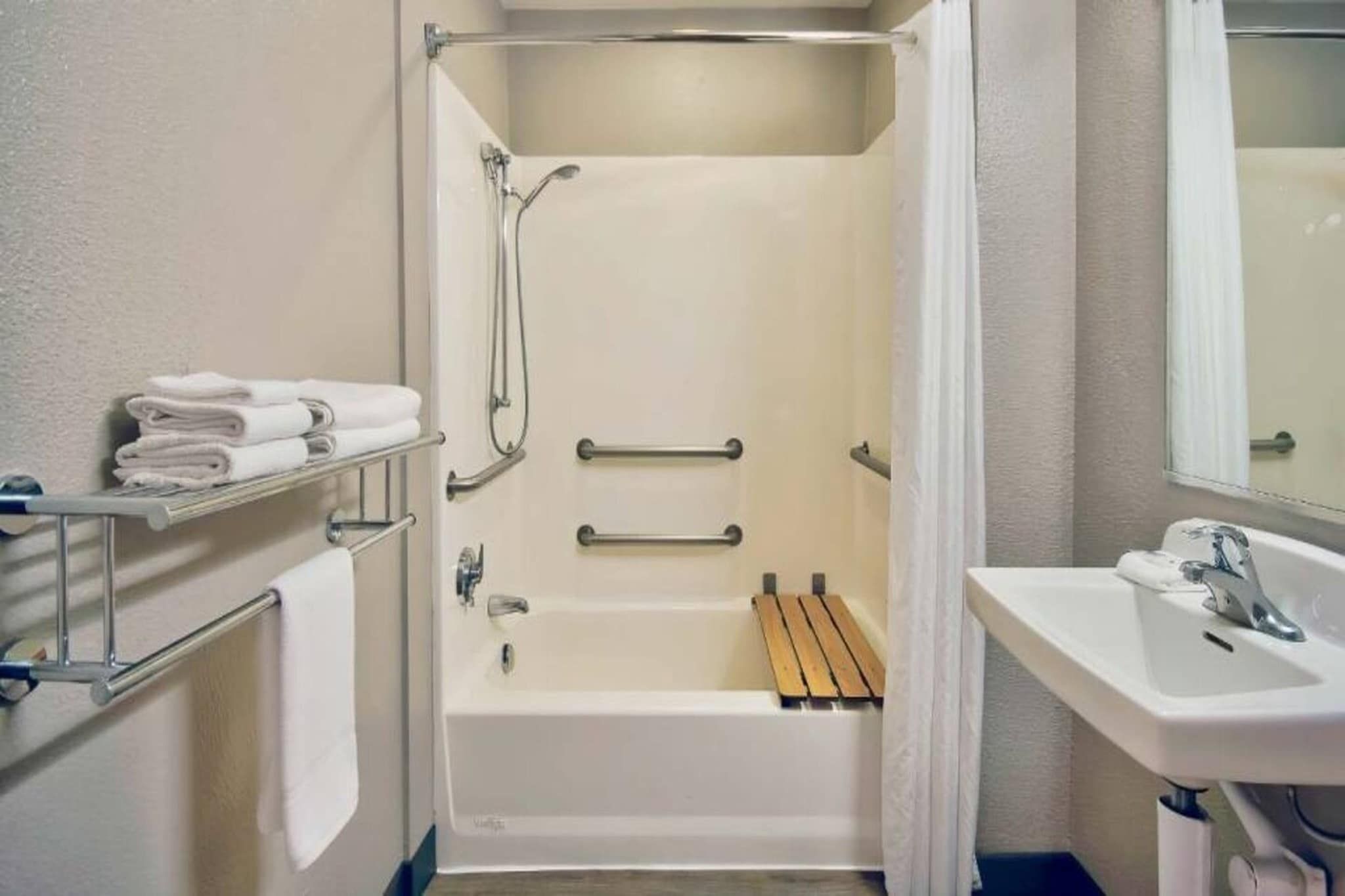 A bathroom with a bathtub, a shower, a sink, and a towel rack.