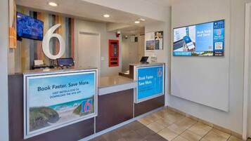 A reception area with a counter, a large number '6' sign, and two digital screens displaying promotional content.