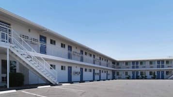 A multi-story motel with a central courtyard, individual rooms with balconies, and a stairwell leading to the upper floors.