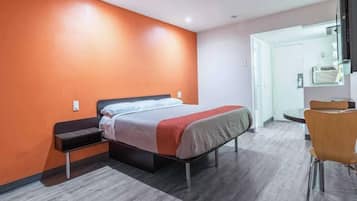 A hotel room with a bed, a desk, and a chair.