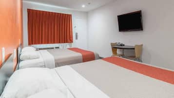 A hotel room with two beds, a desk, a chair, and a television on the wall.