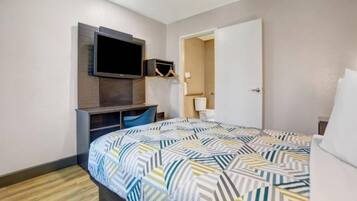A hotel room with a bed, a desk, a television, and a wardrobe.