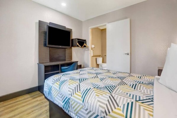Habitació d'hotel amb llit, escriptori, televisió i armari.