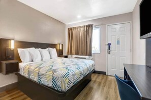 Une chambre d’hôtel avec un lit, une table de chevet, une télévision et une fenêtre avec des rideaux.