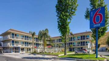 A motel with a large '6 ENTER' sign, multiple balconies, and a parking area.