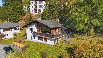 Un chalet à deux étages doté d’un balcon, entouré de forêt.