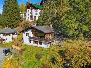 Un chalet à deux étages doté d’un balcon, entouré de forêt.