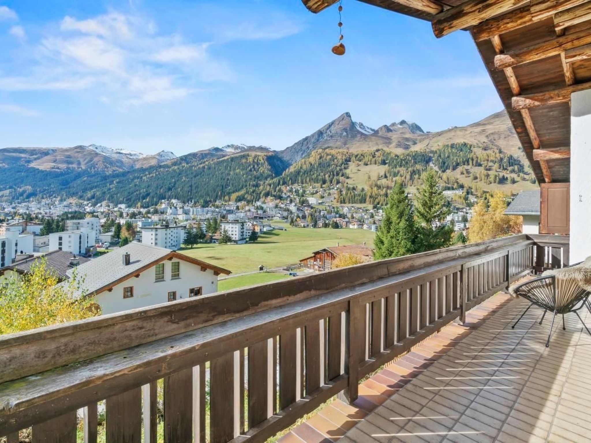 Un balcon doté d’une balustrade en bois, d’où l’on peut admirer une ville et des montagnes.