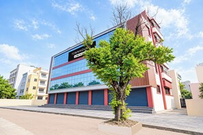 A modern building with a glass facade, a sign reading 'TOWNHOUSE,' and a tree in the foreground. - Townhouse Vishwavidyalaya Metro Station (Kanpur)