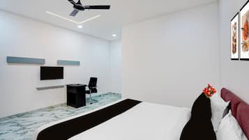 Un dormitorio moderno con cama, escritorio, silla, ventilador de techo y cuadros en la pared.