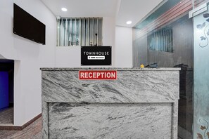 A reception desk with a sign indicating it is serviced by OYO. - Townhouse Vishwavidyalaya Metro Station (Kanpur)