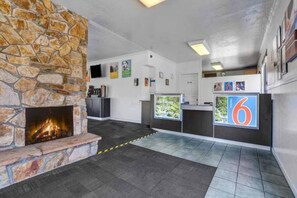 A lobby with a stone fireplace, a reception desk, and a large number '6' sign.