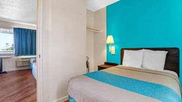 Une chambre d’hôtel avec un lit, une table de chevet, une lampe et une fenêtre avec des rideaux.