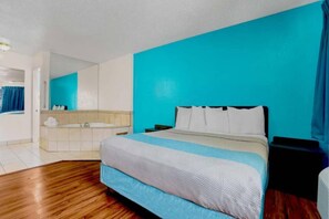 Une chambre à coucher comprenant un lit, une table de chevet, une commode et une salle de bain avec une baignoire.
