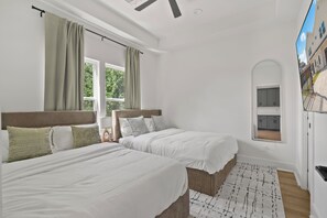 A bedroom with two beds, a window with curtains, a ceiling fan, and a view of the outside. - Designer 4BR Home with Hot tub Gated - sleep 10 (Houston)
