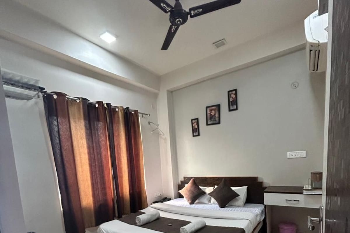 A hotel room with a bed, a desk, a chair, a ceiling fan, and a bathroom.