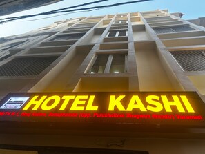 Un letrero de hotel con 'HOTEL KASHI' en letras amarillas brillantes, que indica el nombre del hotel.